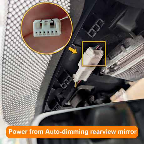 Close-up of a car's auto-dimming rearview mirror with wiring and connectors.